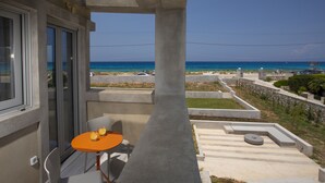 A balcony with a table and chairs, overlooking a beach and a parking area. - Villa Kymo by Thines Villas (Lefkada)