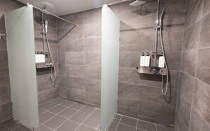 A modern shower area with grey tiles, a glass partition, and a showerhead. - Canvas Black Guesthouse (Busan)