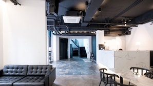 A modern interior with a black leather sofa, a marble-topped table, and a staircase leading to another level.