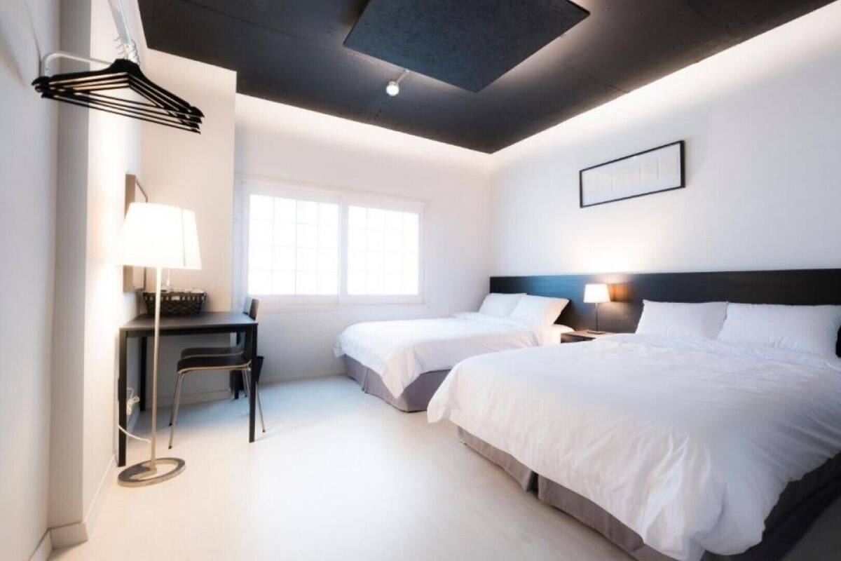 Ein modernes Hotelzimmer mit zwei Betten, einem Schreibtisch und einem Stuhl.