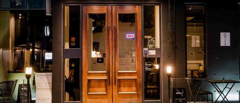 L’entrée d’un hôtel, avec des portes en bois, un comptoir d’enregistrement et un panneau indiquant qu’il est interdit de fumer.