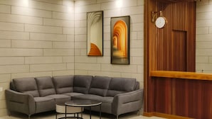 A modern living room with a grey sectional sofa, a small round coffee table, and two abstract paintings on the wall. - ZOOM HOTEL (George Town)