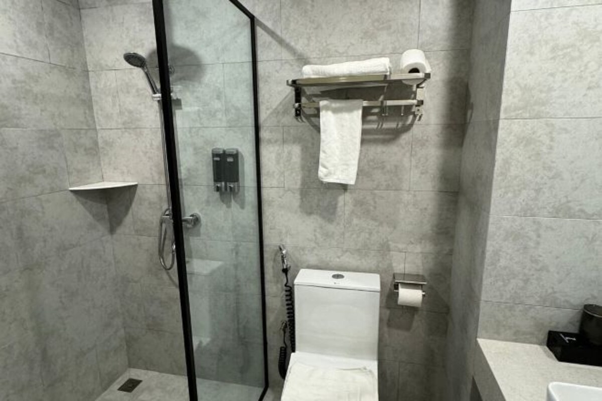 A modern bathroom with a glass-enclosed shower, a toilet, and a towel rack.