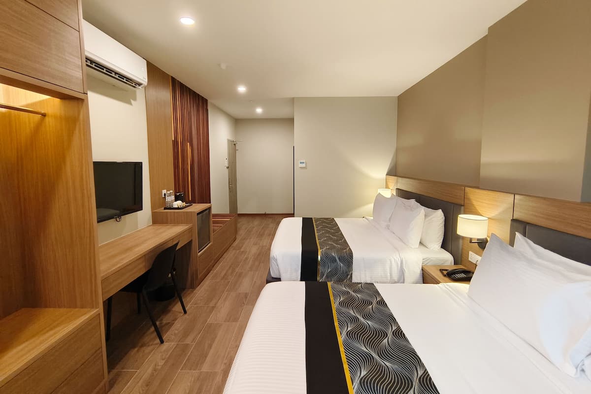 A hotel room with two beds, a desk with a TV, and a minibar.