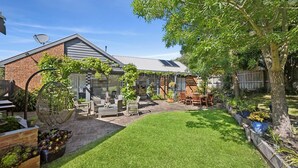 A backyard with a patio, outdoor furniture, and a lawn. - Three Bedroom House with Ocean Views (Torquay)