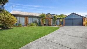 A modern two-story house with a well-maintained lawn, a garage, and a satellite dish. - Three Bedroom House with Ocean Views (Torquay)