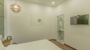 A hotel room with a bed, a television, a picture on the wall, and a bathroom visible through a glass door. - Seven A Hotel (Xuan Huong - Da Lat)