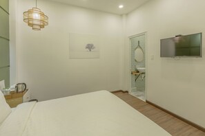 A hotel room with a bed, a television, a picture on the wall, and a bathroom visible through a glass door. - Seven A Hotel (Da Lat)