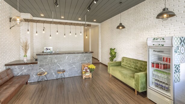 A modern interior with a marble bar, a green sofa, and a refrigerator stocked with beverages. - Seven A Hotel (Xuan Huong - Da Lat)