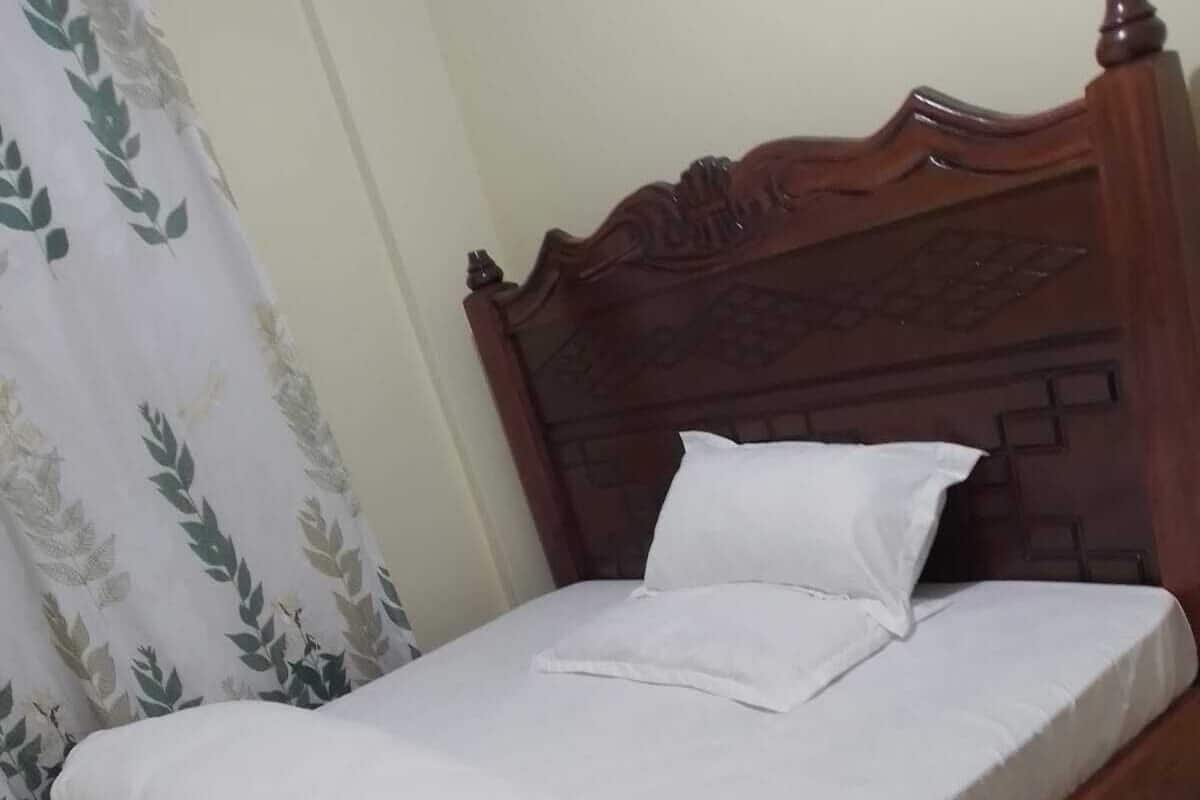 A neatly made bed with white linens and a wooden headboard.