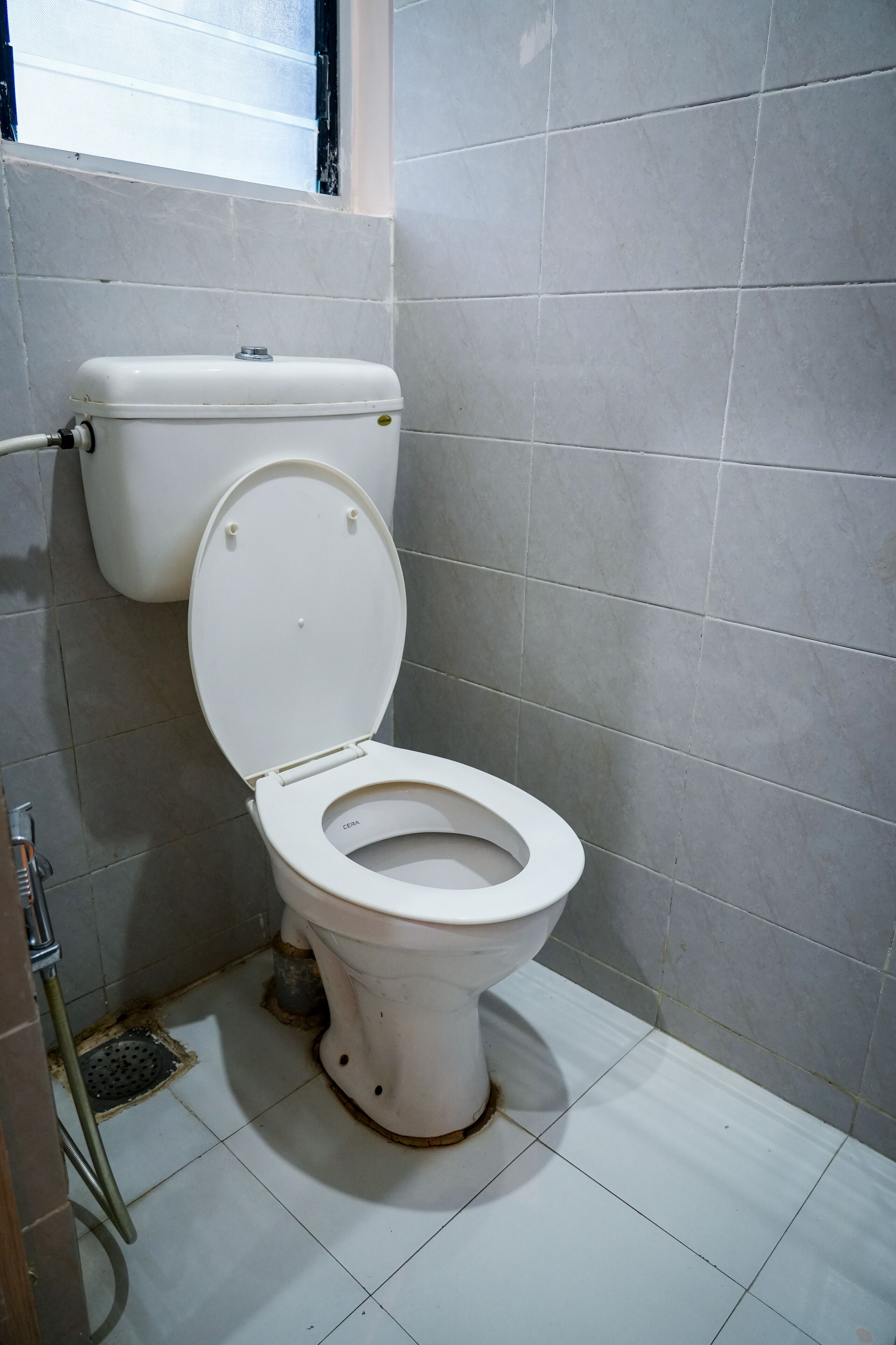 A white toilet with a closed lid, a visible tank, and a floor drain.