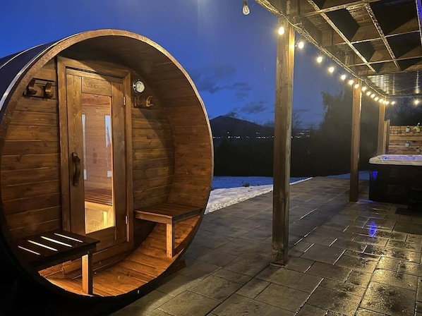 A wooden barrel-shaped room with a bench, a door, and a clock on the wall.