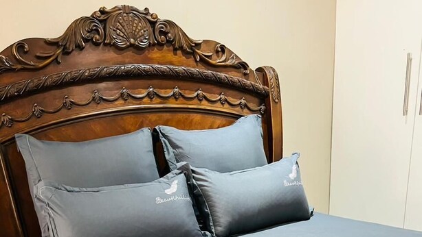 A neatly made bed with a wooden headboard and two pillows. - 295 WELLINGTON (Johannesburg)