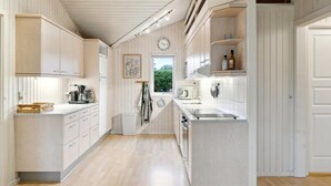 Une cuisine moderne avec des meubles en bois, un four encastré et une fenêtre qui laisse entrer la lumière naturelle.
