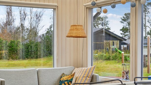Un salon moderne avec un canapé gris, des coussins à rayures et une lampe en osier.