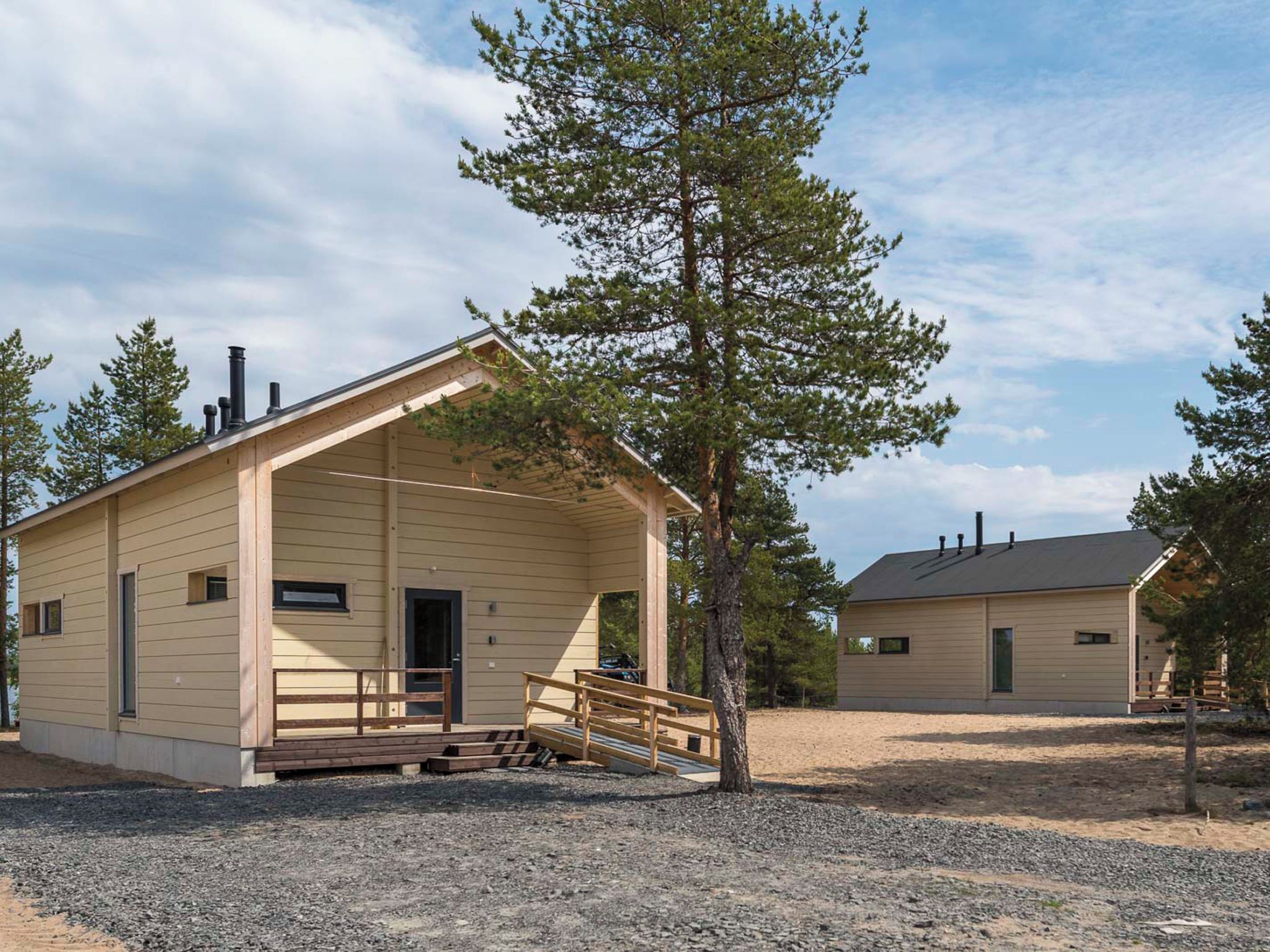 A cabin with a porch and a chimney, surrounded by trees.