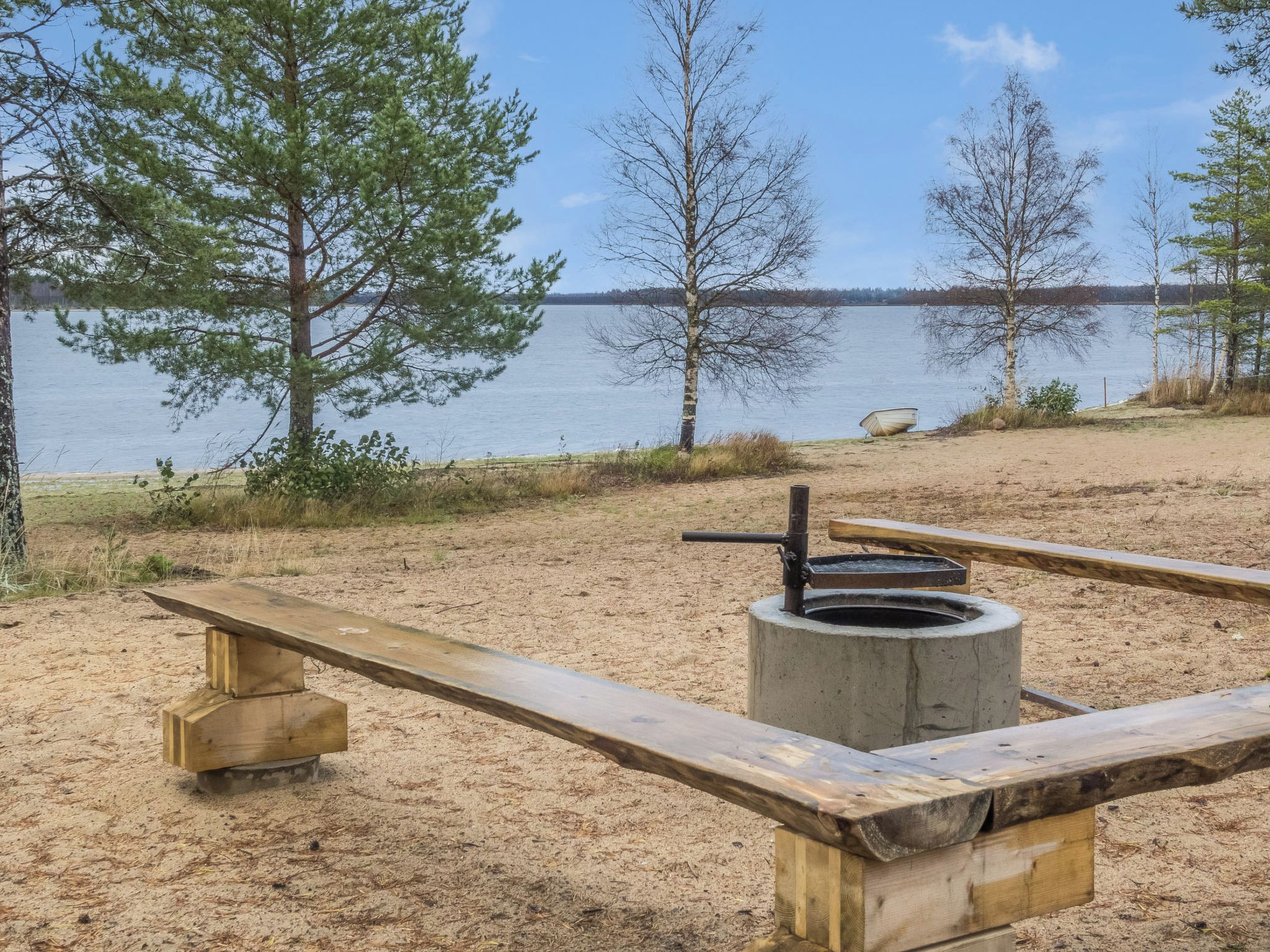 Un terrain de camping équipé d’un foyer, d’une table de pique-nique et offrant une vue sur un lac.