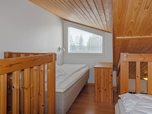 Una habitación pequeña y funcional con una cama individual, ventana con persianas y muebles de madera.
