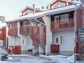 Un edificio residencial de varios pisos con una escalera central, balcones y un garaje.