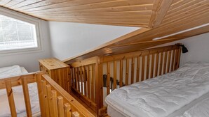 Une chambre à coucher avec un lit superposé en bois et une fenêtre équipée de stores.