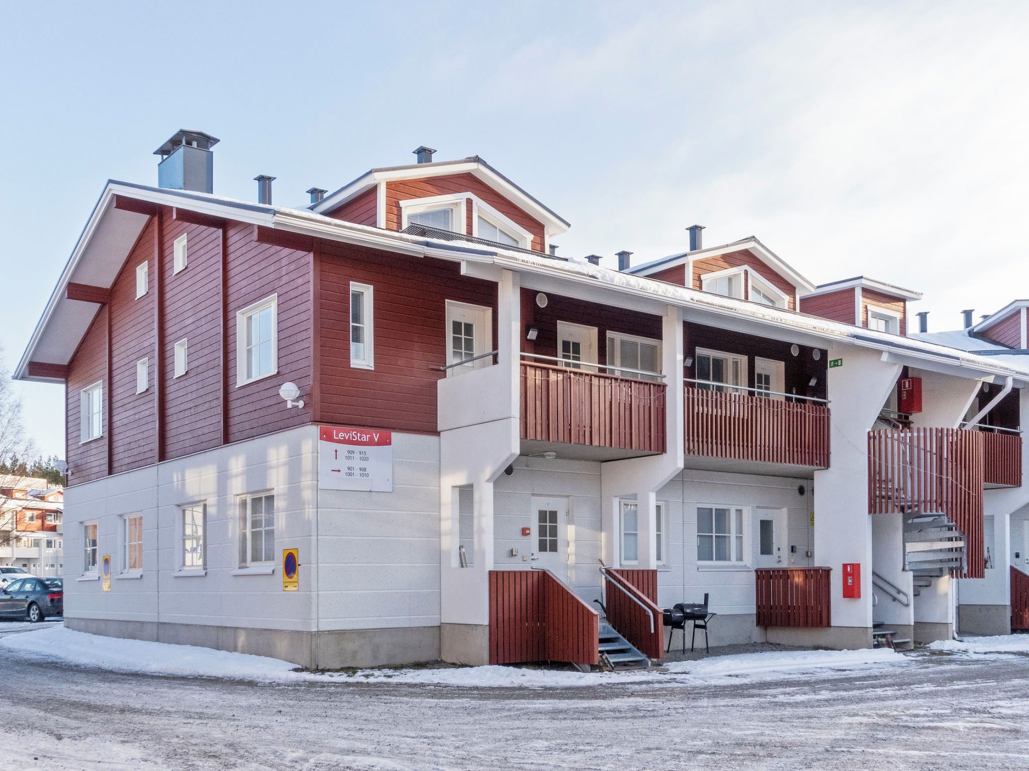Monikerroksinen rakennus, jonka ulkoseinät ovat punaiset ja valkoiset, toisessa kerroksessa on parveke ja sisäänkäyntiin johtavat portaat.