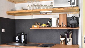 Een kleine keuken met een magnetron, waterkoker en koffiezetapparaat op een houten aanrecht.