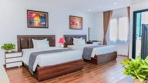 Une chambre d’hôtel avec deux lits, une table de chevet avec une lampe, une plante en pot et des œuvres d’art accrochées aux murs.