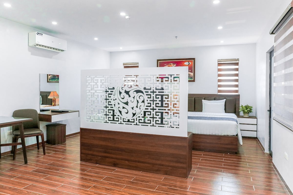 Une chambre d’hôtel moderne équipée d’un lit, d’un bureau, d’une chaise et d’un panneau décoratif mural.