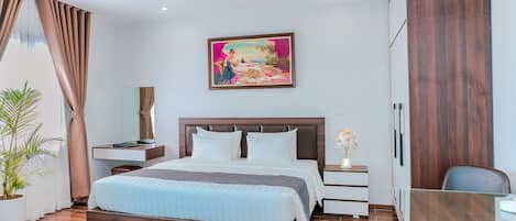A modern hotel room with a large bed, bedside tables, a desk, and a painting on the wall.