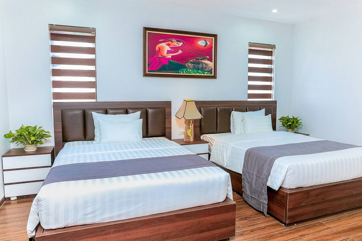 Un lit double avec une tête de lit en bois, une table de chevet avec une lampe et un tableau accroché au mur.