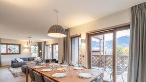A dining area with a wooden table set for four, surrounded by grey upholstered chairs.