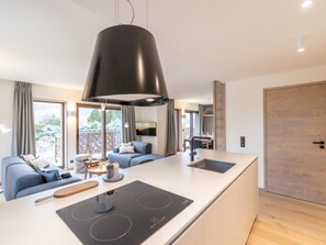 Een moderne keuken met een centraal eiland, een eethoek met een tafel en stoelen, en een zithoek met een bank en salontafel.