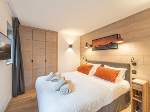 Een moderne slaapkamer met een groot bed, een houten garderobe en een schilderij aan de muur.