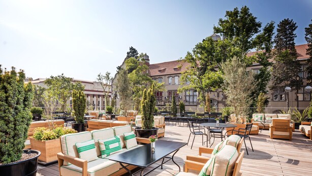 An outdoor seating area with wooden furniture and potted plants.