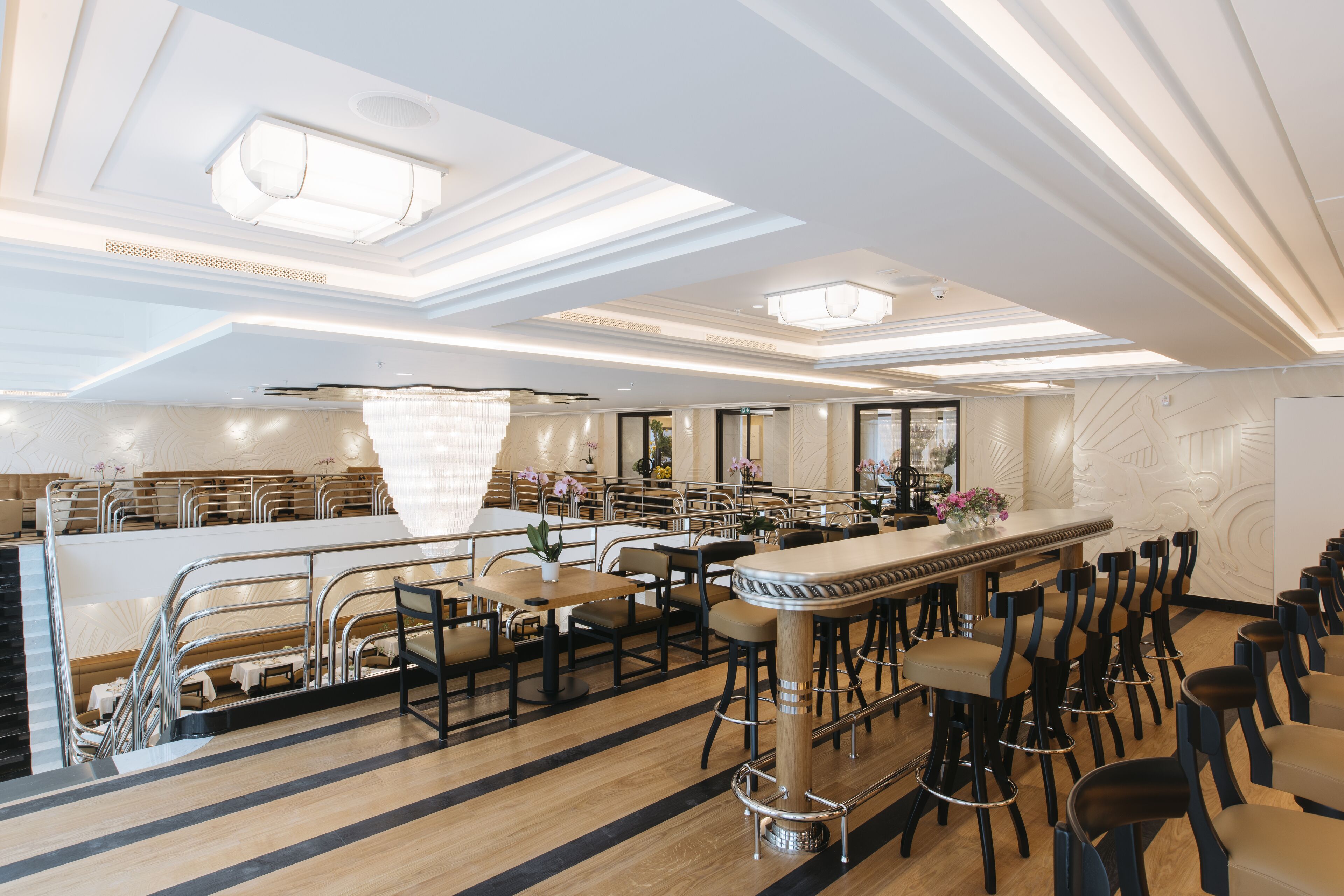 A modern restaurant with a bar area, high ceilings, and a clean, elegant interior design.