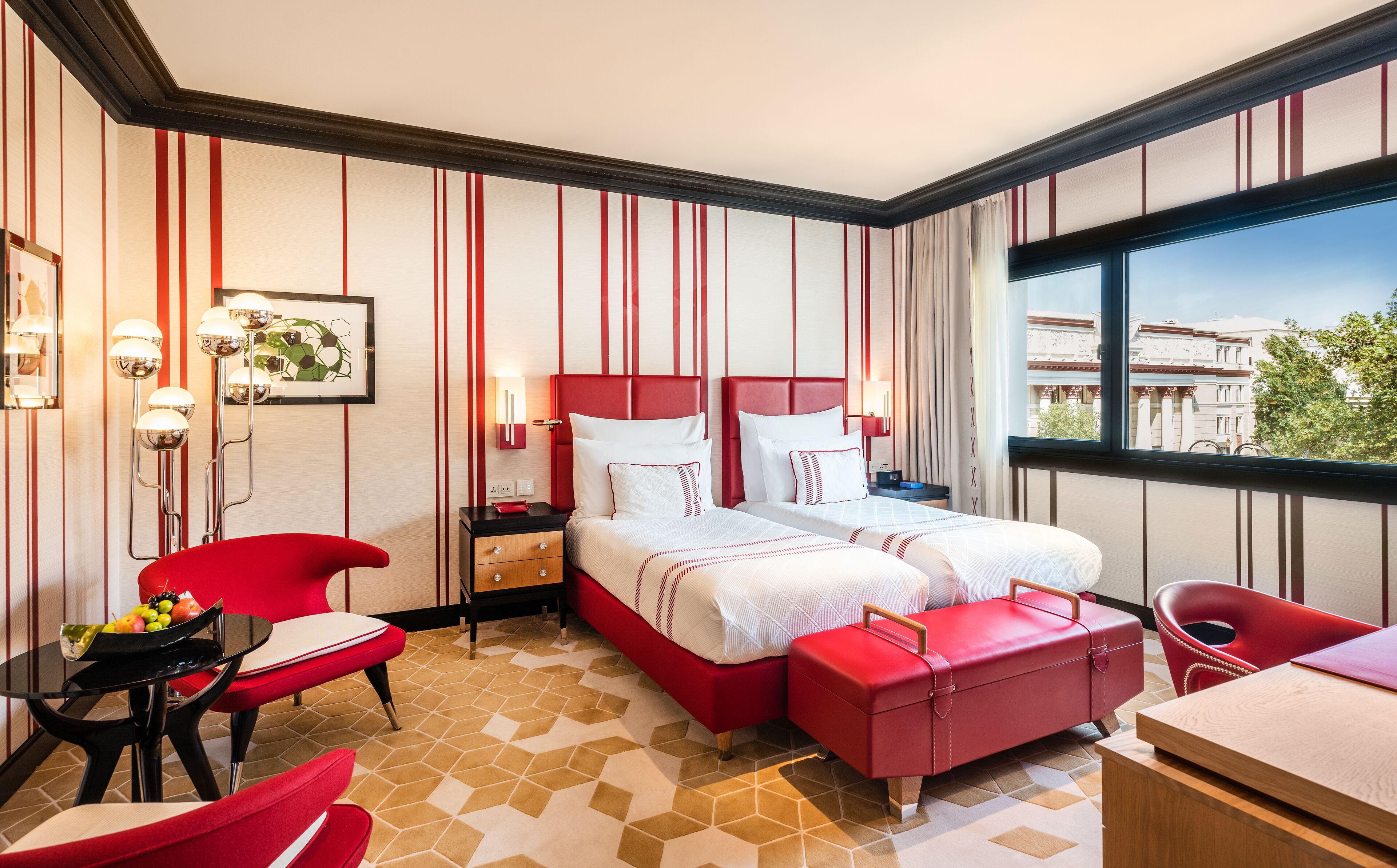 Une chambre d’hôtel avec un lit, un bureau, une chaise et une vue sur l’extérieur.