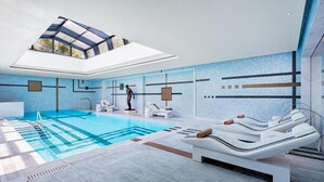 Una piscina interior moderna con tragaluces, sillones de descanso y una tumbona.
