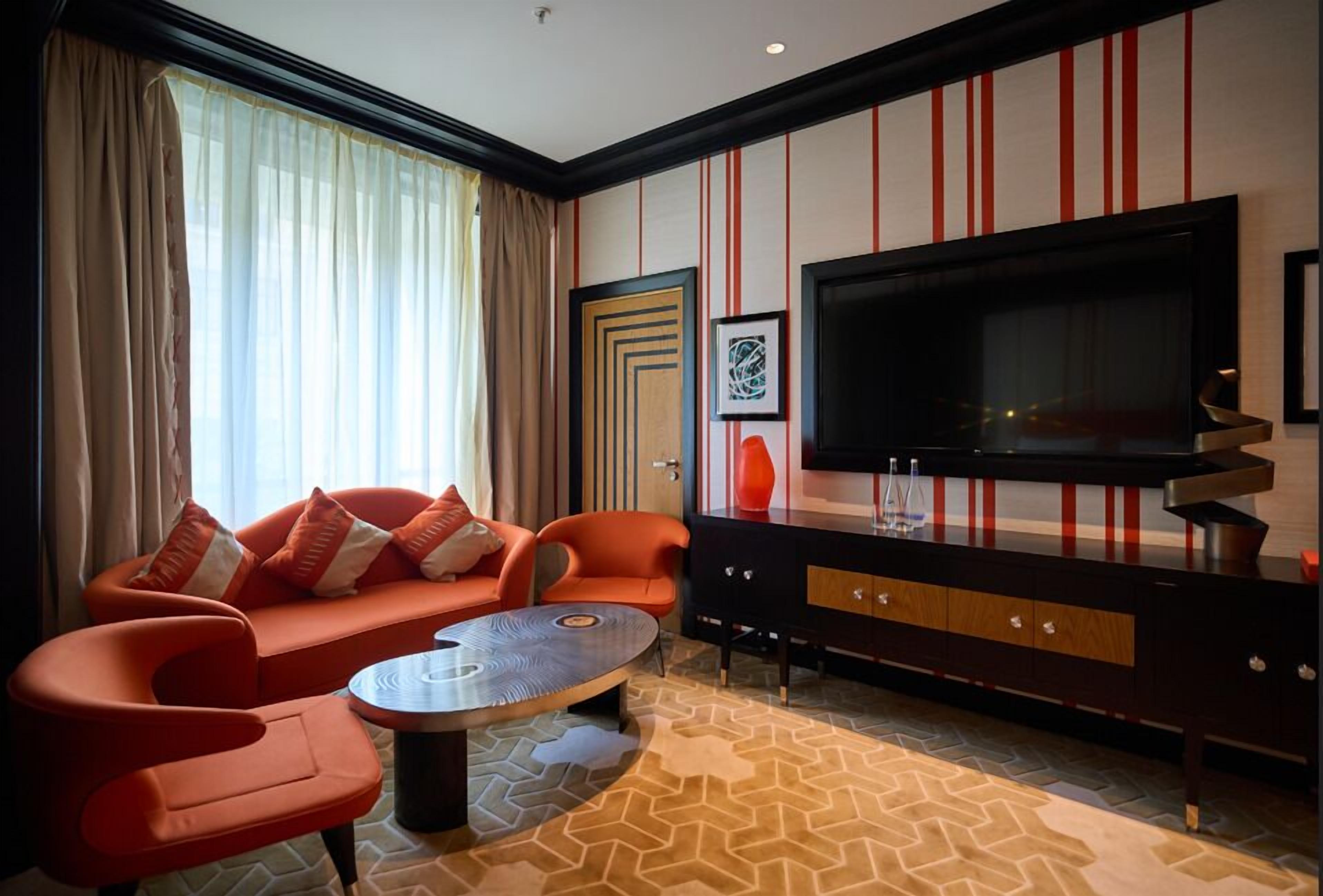 A modern living room with a sofa, chairs, a coffee table, a TV, and a cabinet.