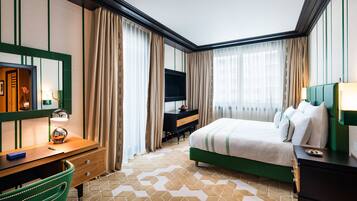 A hotel room with a bed, a desk, a chair, a TV, and a mirror.