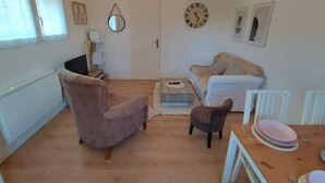 A spacious living room with a sofa, armchair, and a dining table set for four.