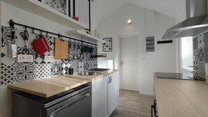 A modern kitchen with a dishwasher, a sink, and a stove. There are patterned tiles on the backsplash and a wooden countertop.
