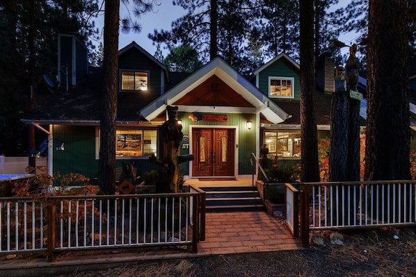 A two-story house with a front porch, a wooden door, and a sign that reads 'ST.'