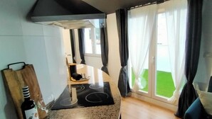 Eine moderne Küche mit einer Granitabdeckung, einer Weinflasche und einem Glas. Ein schwarzer Stuhl und ein Fenster mit Vorhängen sind ebenfalls vorhanden.