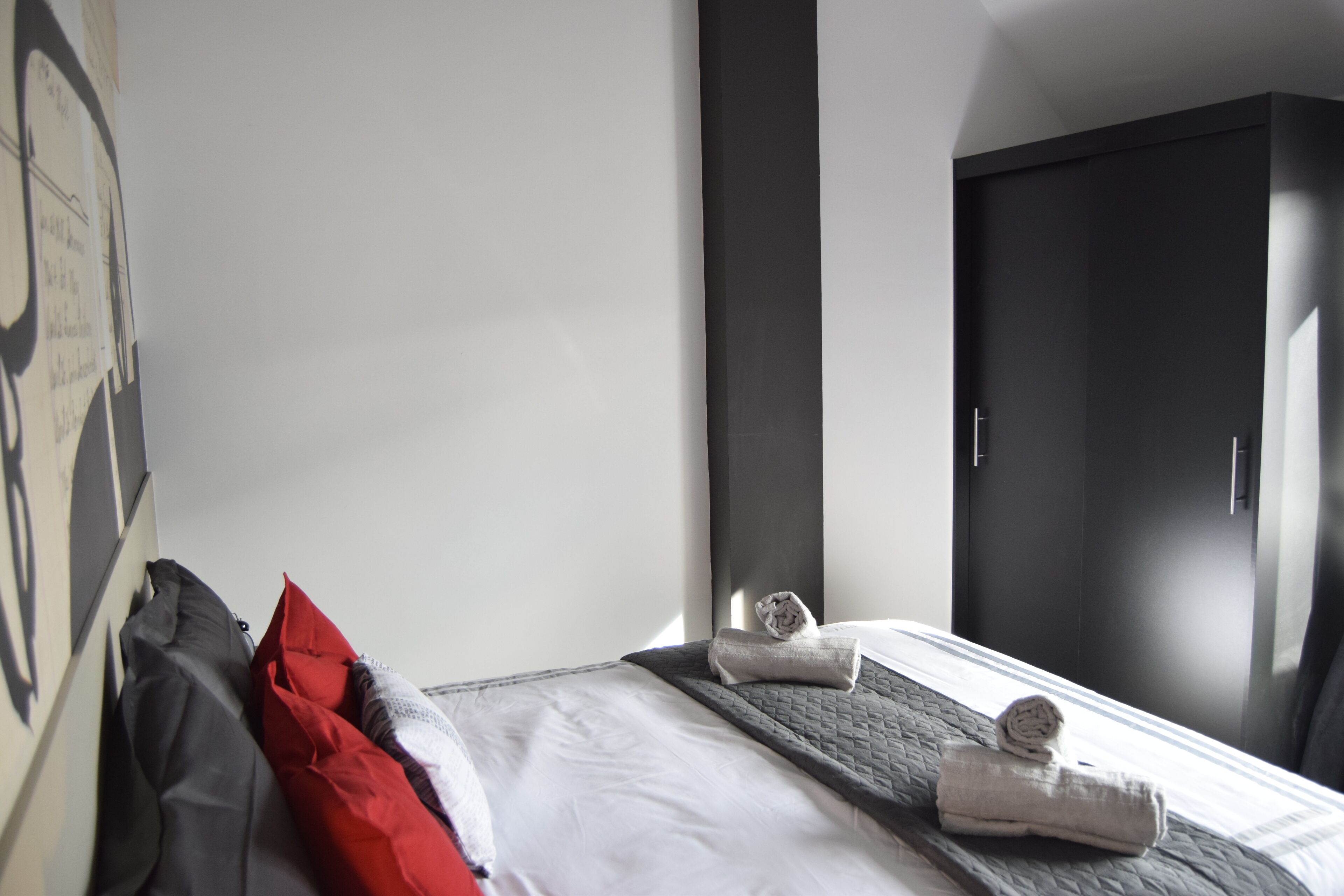 Habitación de hotel con cama, almohadas, toalla, armario y un cartel en la pared.