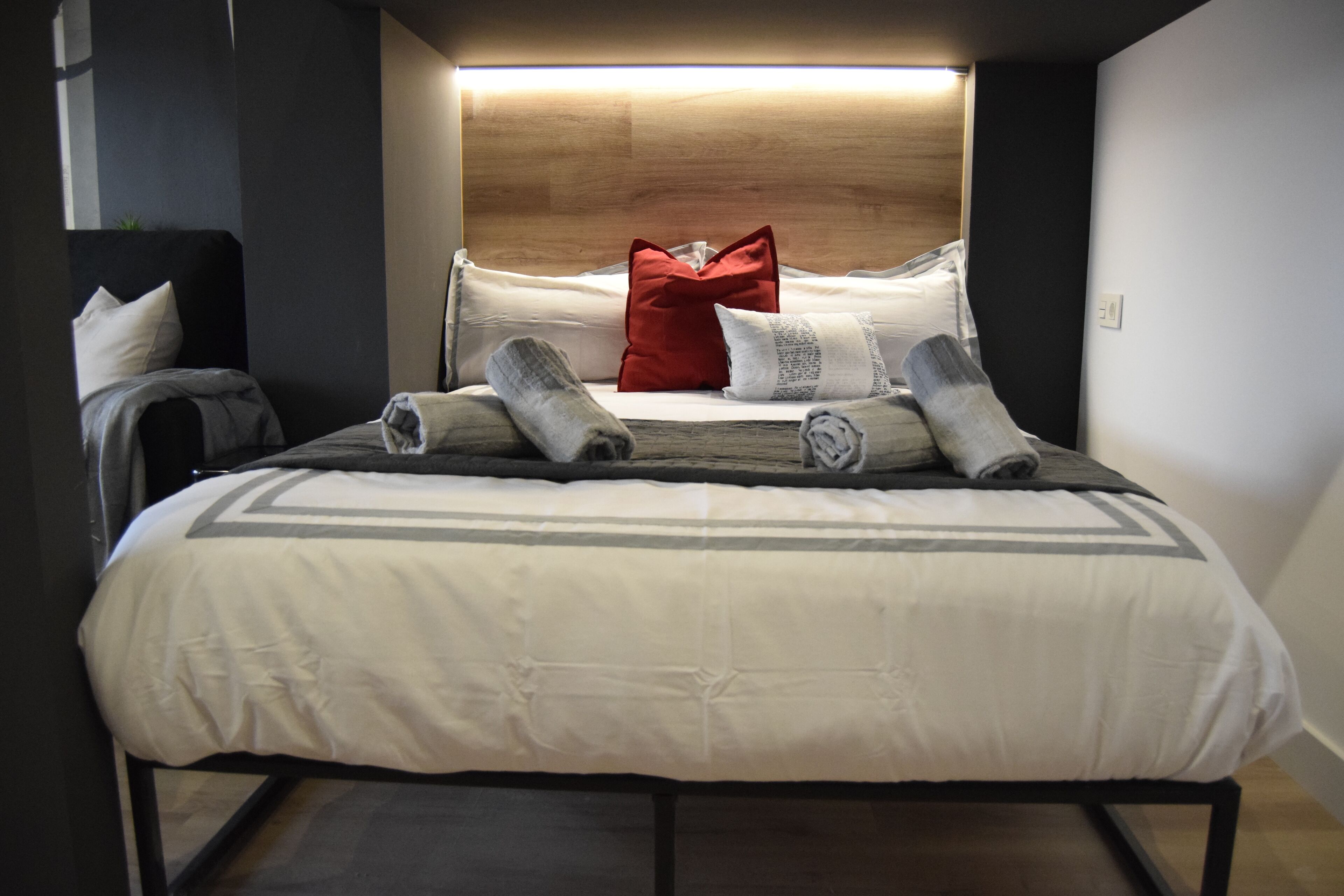 Een net opgemaakt bed met hoofdbord, kussens en dekens.