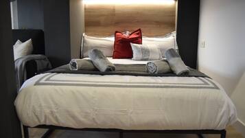 Een net opgemaakt bed met hoofdbord, kussens en dekens.