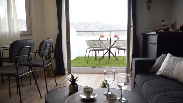 En moderne stue med en sofa, et sofabord med kopper og glas, og et spiseområde med stole og et bord.