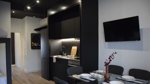 Et moderne køkken med spiseplads, et fladskærms TV på væggen og et lille sofabord med en vase.