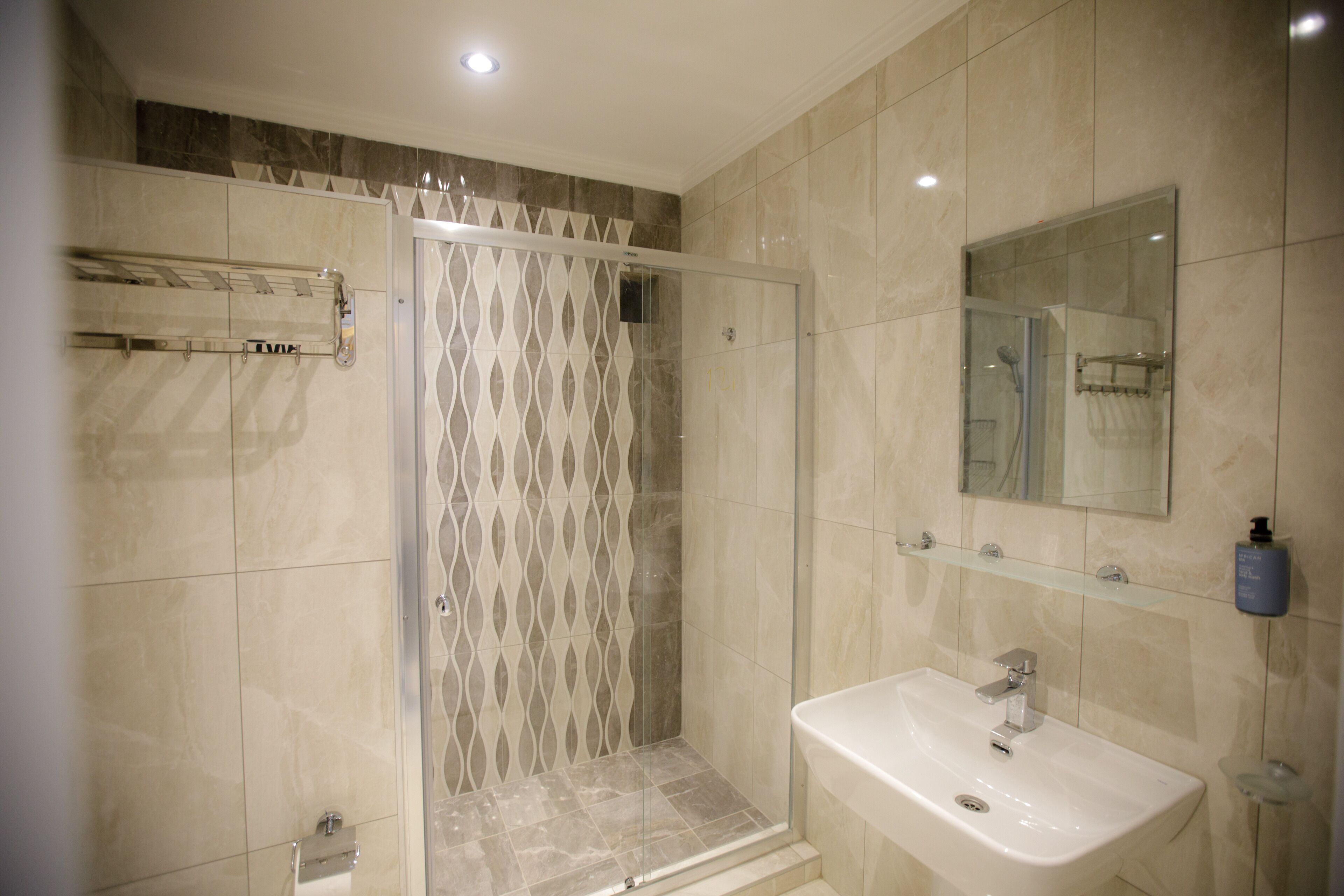 Un bagno moderno con doccia vetrata, lavandino bianco e specchio soprastante.