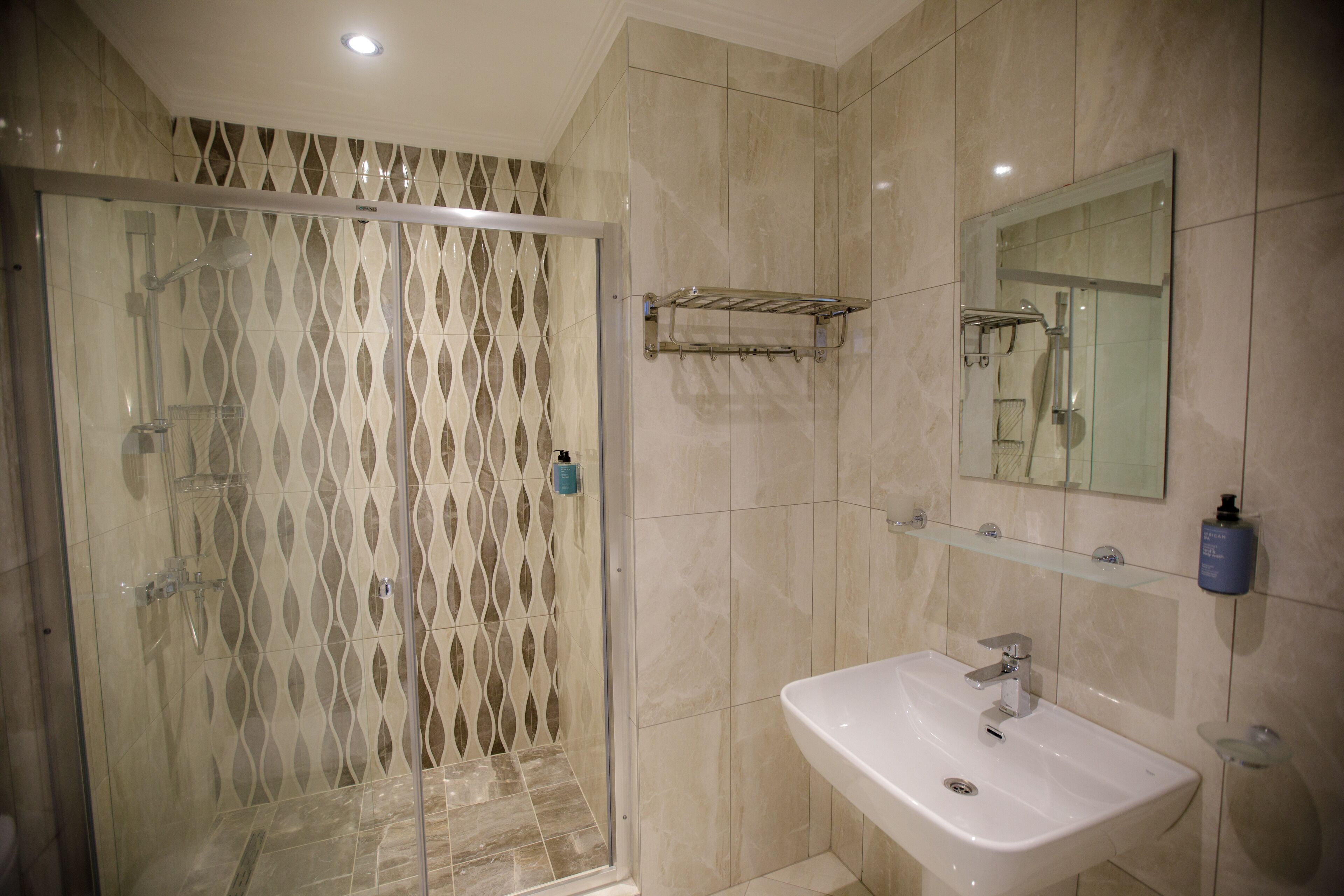 Un baño con cabina de ducha de vidrio, un lavabo y un espejo.